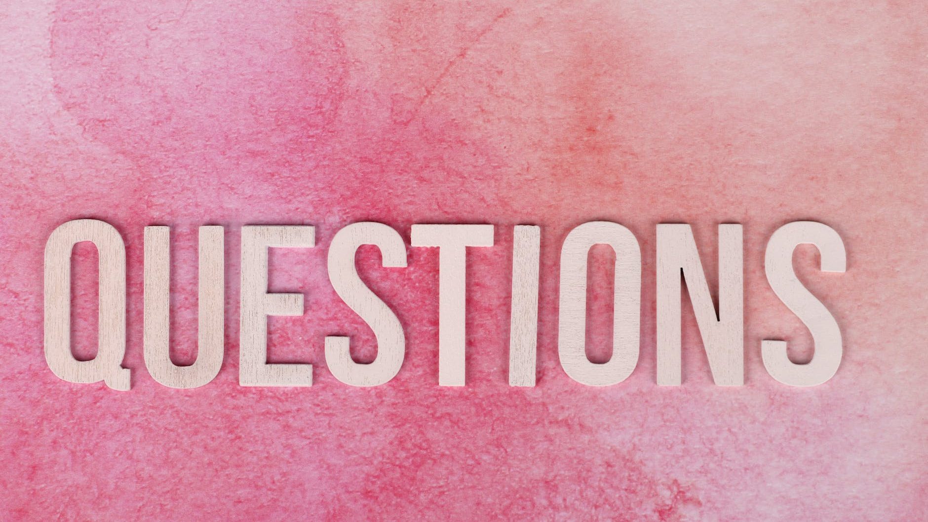 questions text on a pink surface